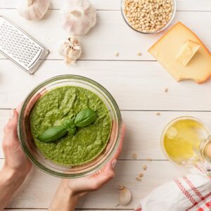 Preparing italian pesto sauce. Woman hands holding homemade pesto bowl